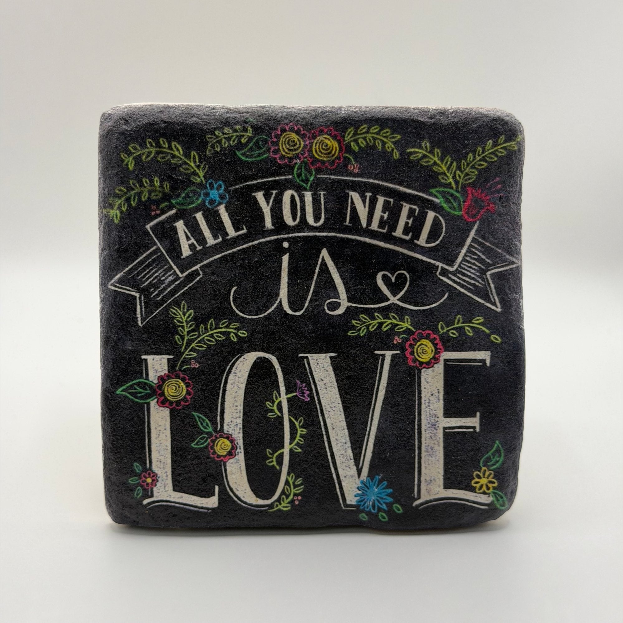 Quotable phrase 'All You Need is Love' printed on square travertine stone coaster
