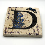 Alphabet letter D design printed on a natural stone coaster