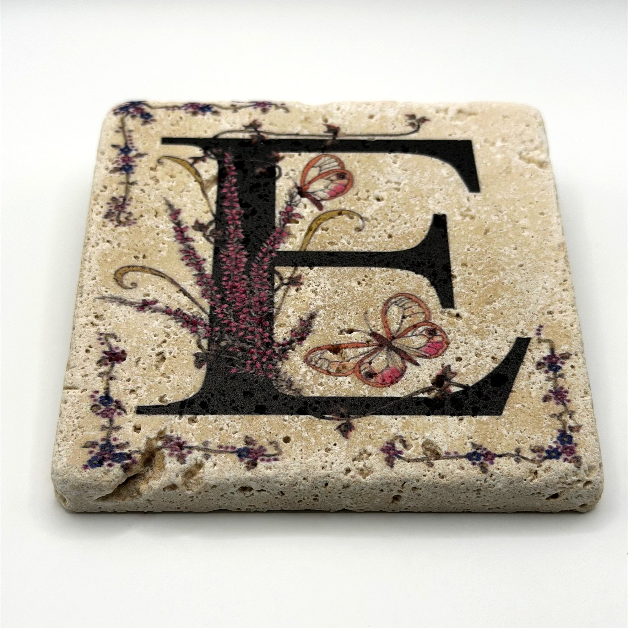 Alphabet letter E design printed on a natural stone coaster