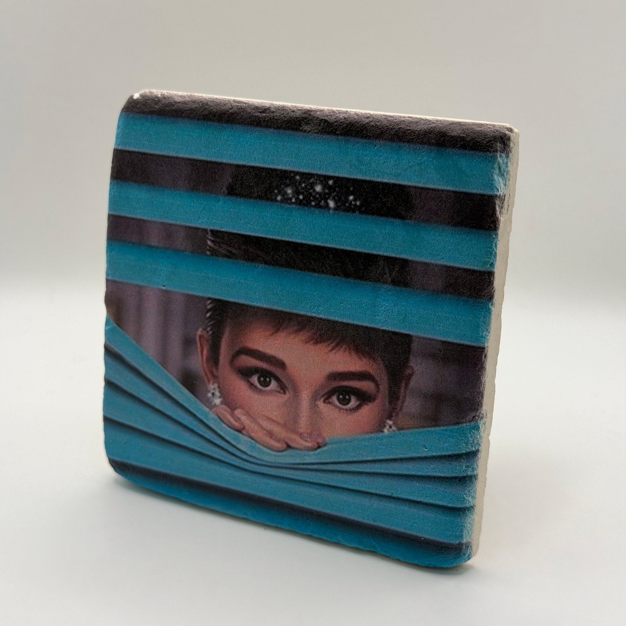 Black and white photograph of Audrey Hepburn printed on square travertine stone coaster