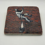 Banksy's Create Escape artwork printed on square travertine stone coaster