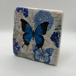Delicate blue butterfly artwork printed on square travertine stone coaster