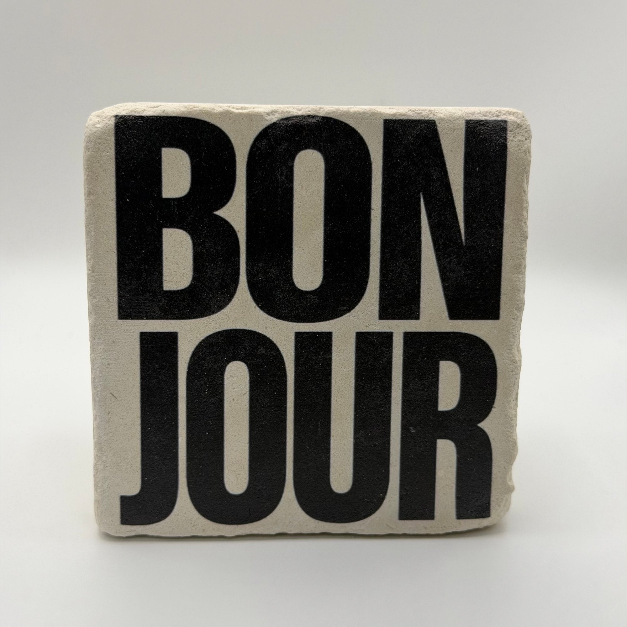 French phrase 'Bonjour' printed on square travertine stone coaster