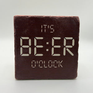 Funny quote 'It's beer o'clock' printed on square travertine stone coaster