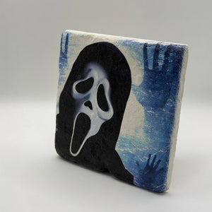 Skull artwork featuring a screaming face printed on square travertine stone coaster