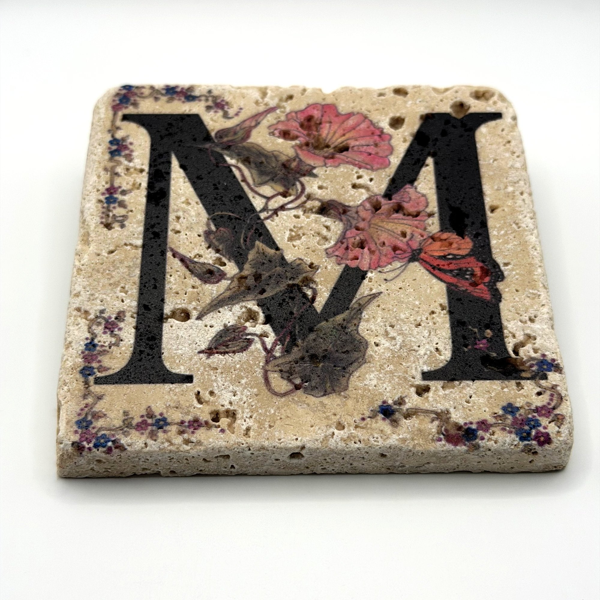 Alphabet letter M design printed on a natural stone coaster