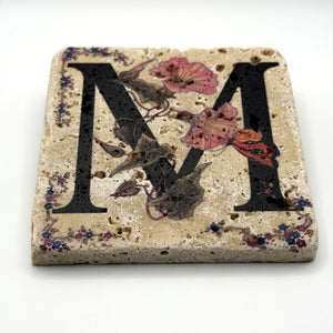 Alphabet letter M design printed on a natural stone coaster