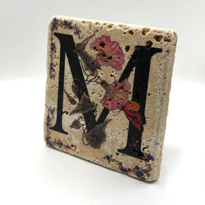 Alphabet letter M design printed on a natural stone coaster