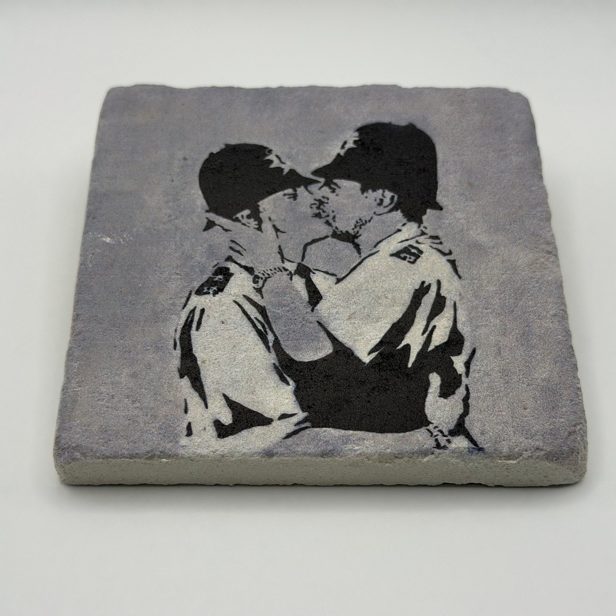 Banksy artwork featuring kissing coppers printed on square travertine stone coaster