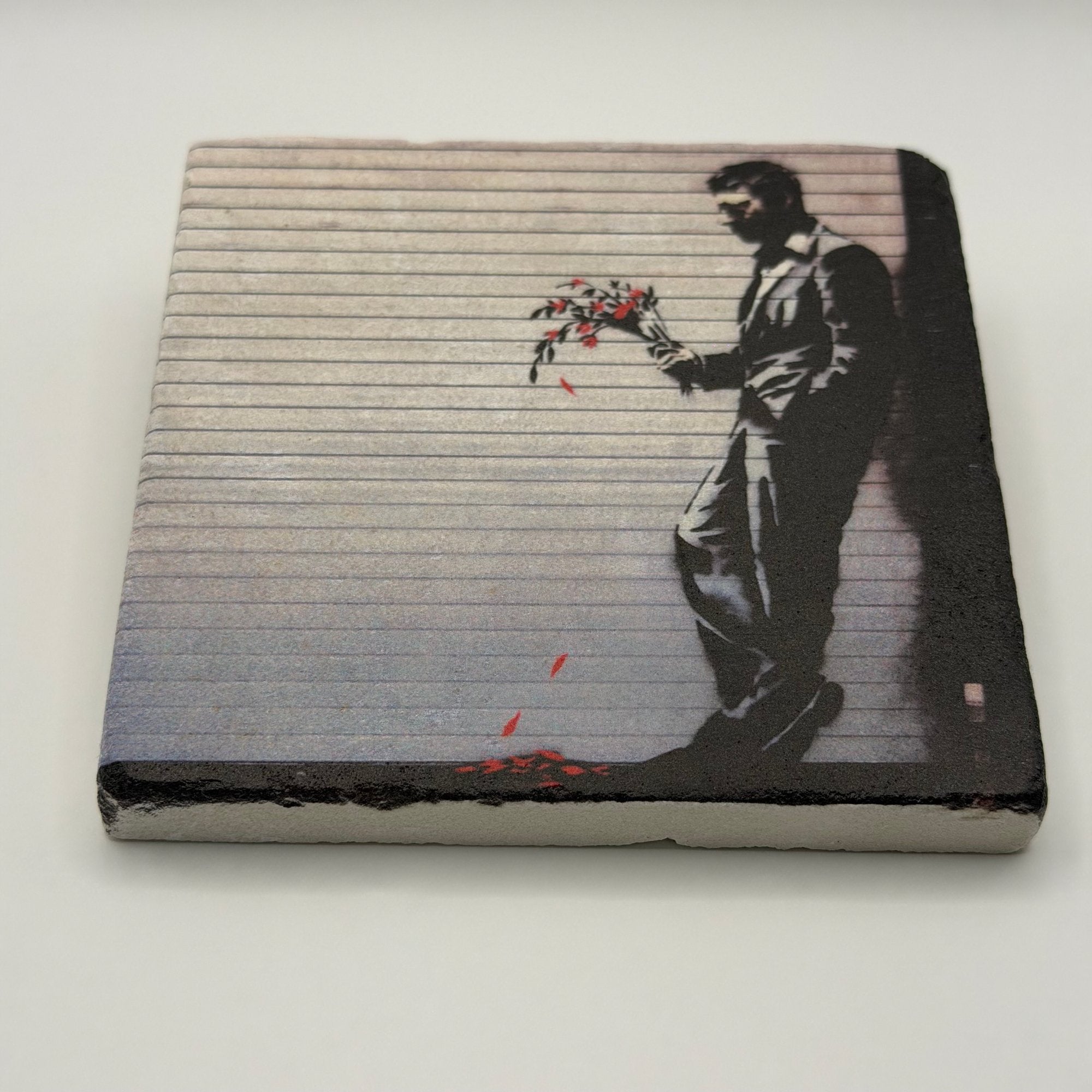 Banksy's iconic artwork 'Waiting In Vain' printed on square travertine stone coaster