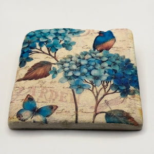 Illustrated bird, flower, and butterfly artwork printed on square travertine stone coaster