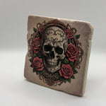 Grungy skull artwork surrounded by roses printed on square travertine stone coaster