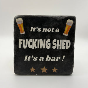Funny quote 'It's Not a Fucking Shed It's a Bar' printed on square travertine stone coaster