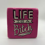 Sarcastic quote 'Life is a Bitch' printed on square travertine stone coaster